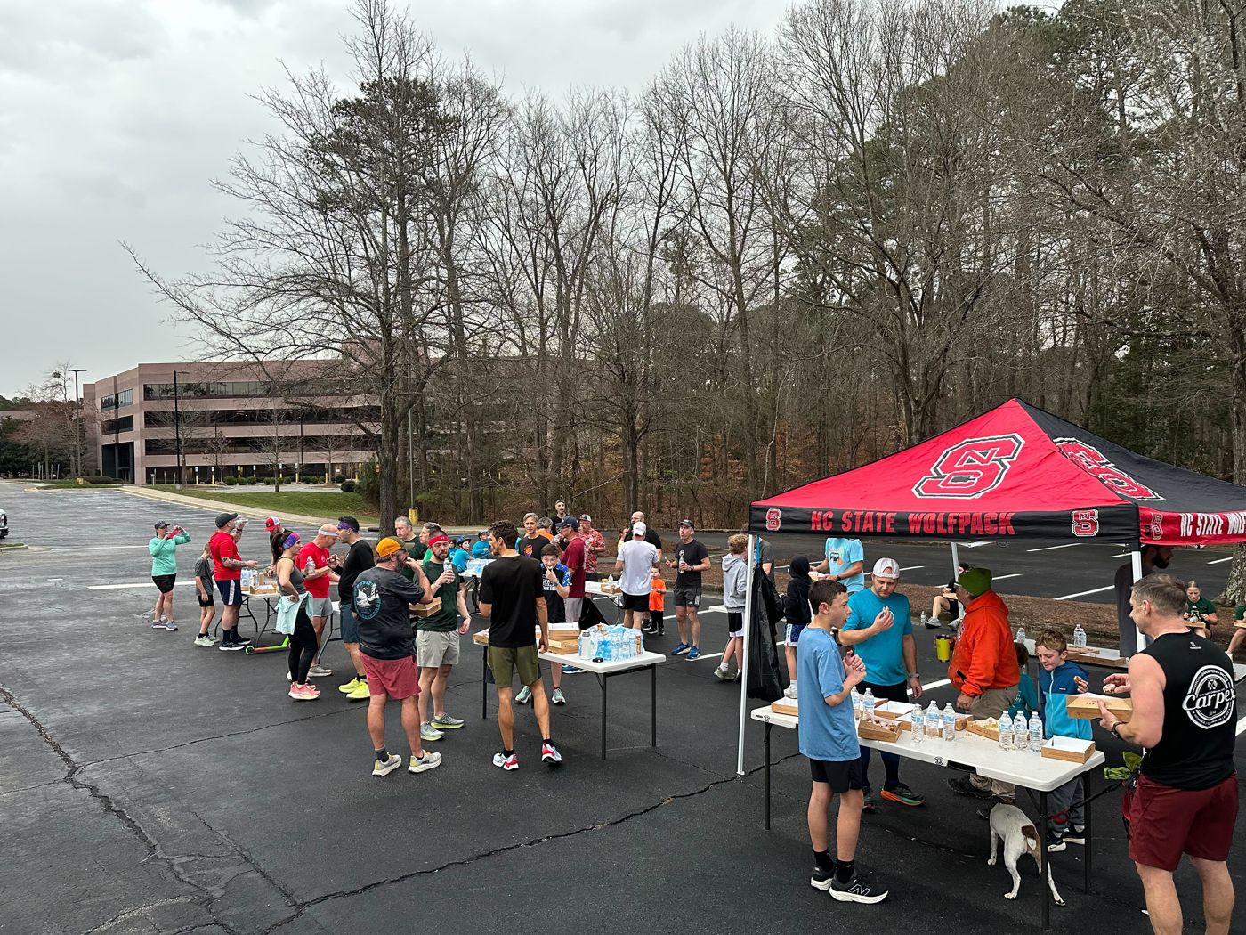 Runners and families eating donuts in a parking lot at the Duck Donuts Dash